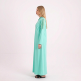 Side view of our blonde model in the bright mint abaya on a white background
